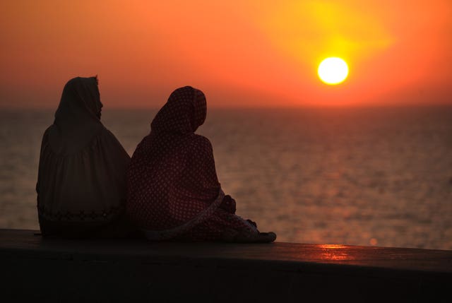 Two women watch the sun set from Marine Drive in Mumbai, India