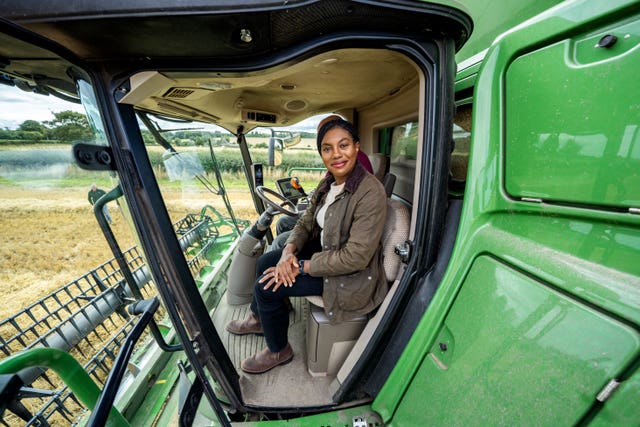 Kemi Badenoch smiling while seated in the cab of a green farm vehicle