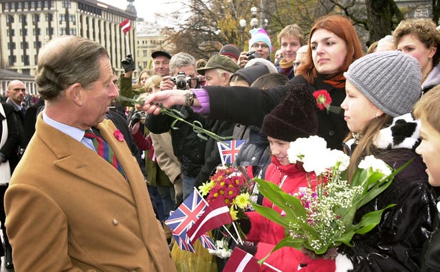 The Prince of Wales is slapped around the face with a flower by a war protester in Latvia (John Stillwell/PA)