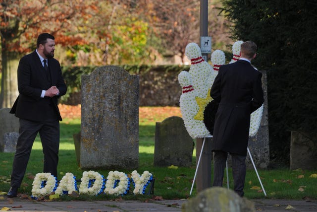 A funeral director places floral tribute which says 'Daddy' in the churchyard at the funeral service of One Direction singer Liam Payne