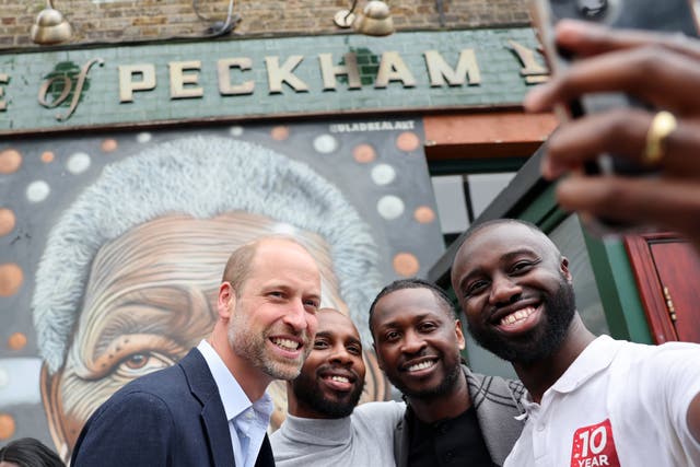 Prince of Wales posing for a selfir with three men outside a pub