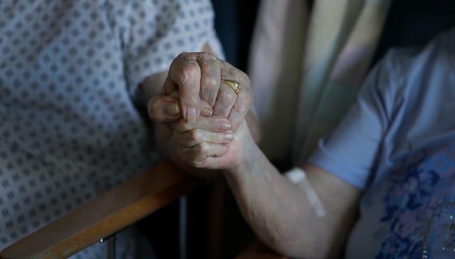 A husband and wife hold hands in a hospital