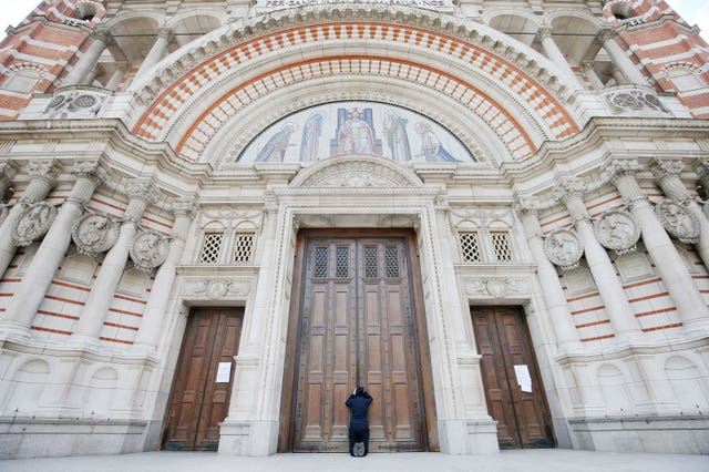 A woman praying at the closed doors of Westminster Cathedral
