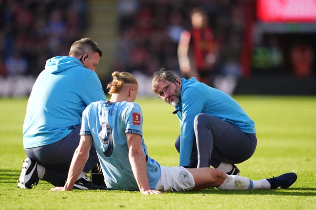 Manchester City striker Erling Haaland sits on the floor as medical staff assess his injured leg
