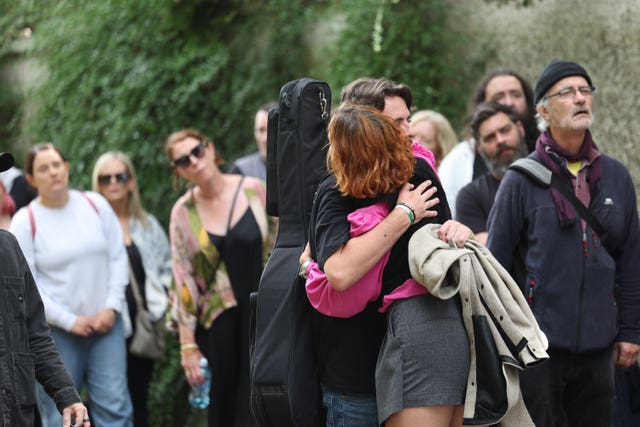 People hug while queueing for the public wake