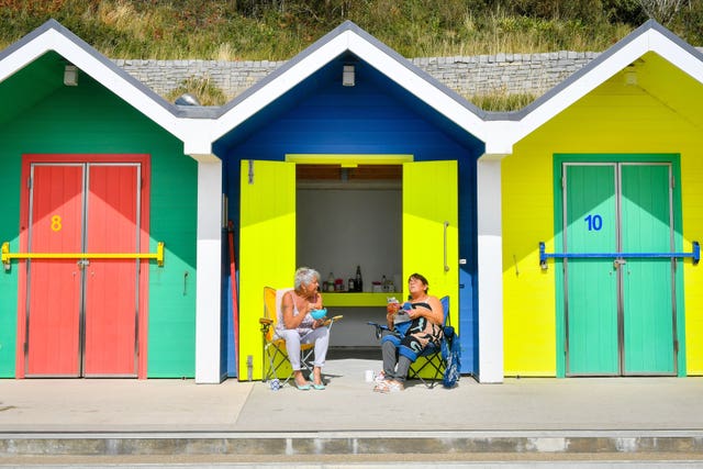 People relaxing by beach huts in Barry