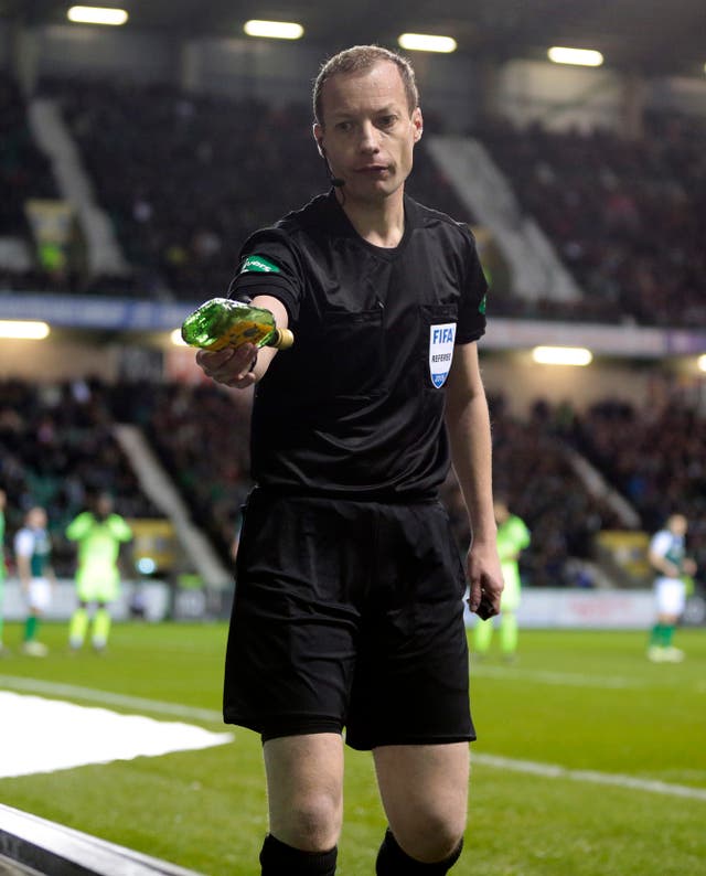 Referee Willie Collum removes a bottle from the pitch during Hibernian's clash with Celtic 