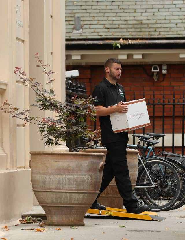 A removal man carrying what appears to be a case of wine from the Carlton Gardens residence (Jonathan Brady/PA)