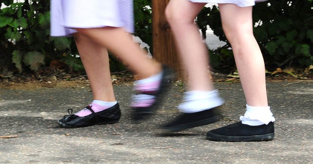 The legs of two school girls in a playground, wearing school uniform