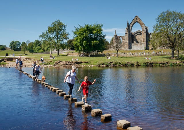 Crossing the stepping stones on the River Wharfe in front of Bolton Abbey