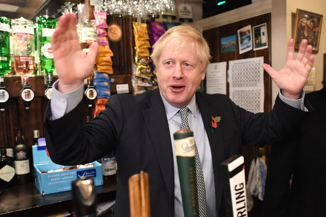 Prime Minister Boris Johnson steps behind the bar to pull a pint as he meets with military veterans at the Lych Gate Tavern in Wolverhampton