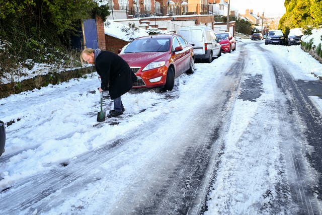 A man on a road digging snow