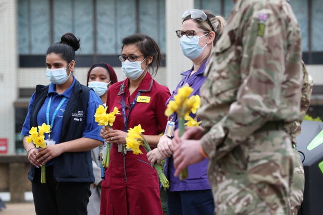Staff and military personnel hold flowers