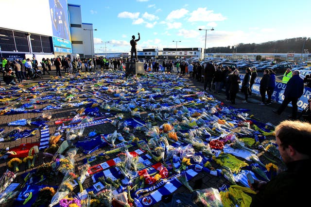 Fans look on at the flowers and scarves placed outside Cardiff City Stadium in tribute to Emiliano Sala