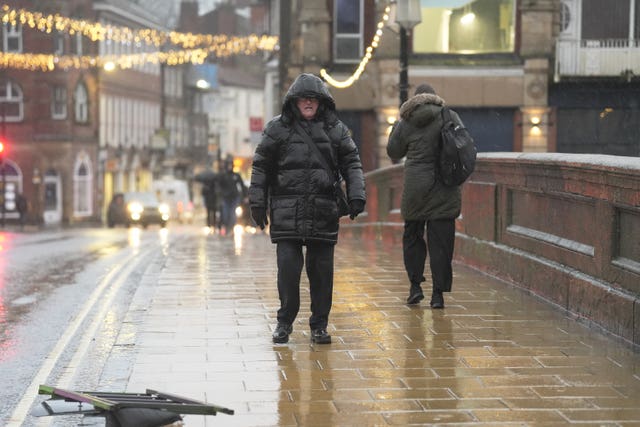 A person standing on a bridge in York wearing a big black coat with their hood up