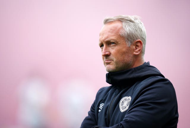 Neil Critchley watches on amid a background of maroon smoke