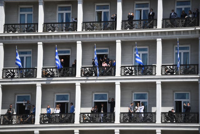 People watch from balconies of a building overlooking the Independence Day Military Parade in Syntagma Square