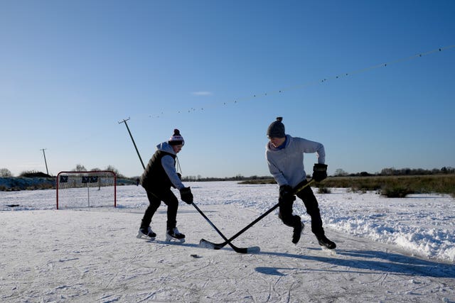People playing ice hockey on a frozen flooded field in Upware, Cambridgeshire