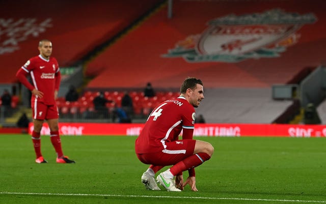 Jordan Henderson crouches on the pitch after his injury against Everton