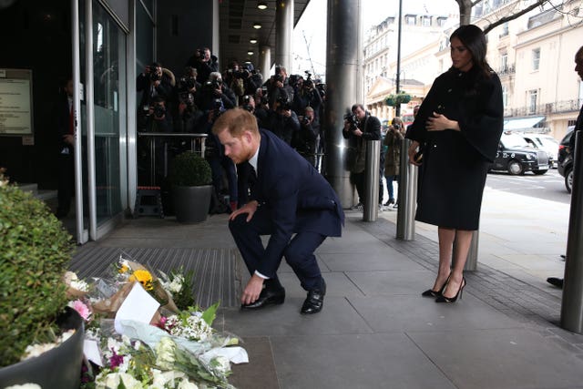 The Duke of Sussex leaves flowers, watched by the Duchess of Sussex, as they arrive at New Zealand House in London