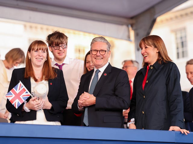 Angela Rayner, Keir Starmer and Rachel Reeves stand together laughing, hoping union flags