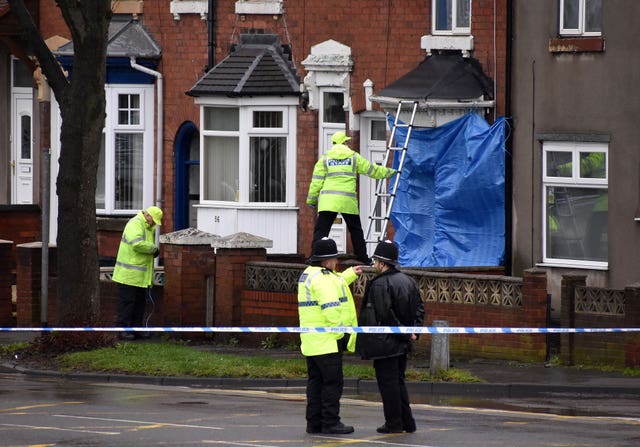 Police staff cover broken windows of a property on Pensnett Road, Brierley Hill, after the murder inquiry was launched