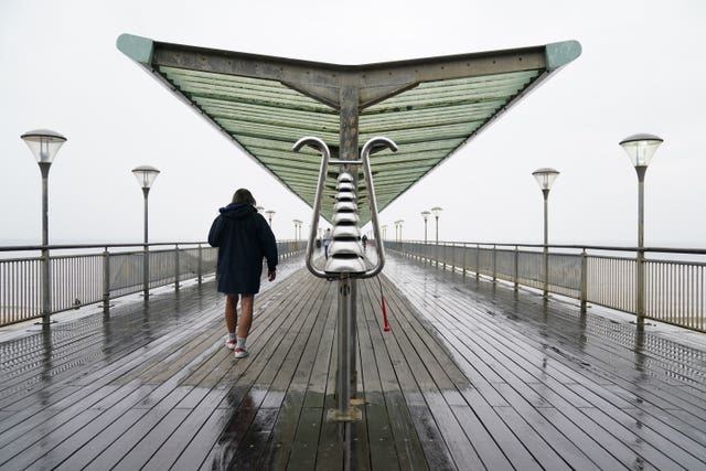 A person makes their way through the rain along Boscombe Pier in Dorset.