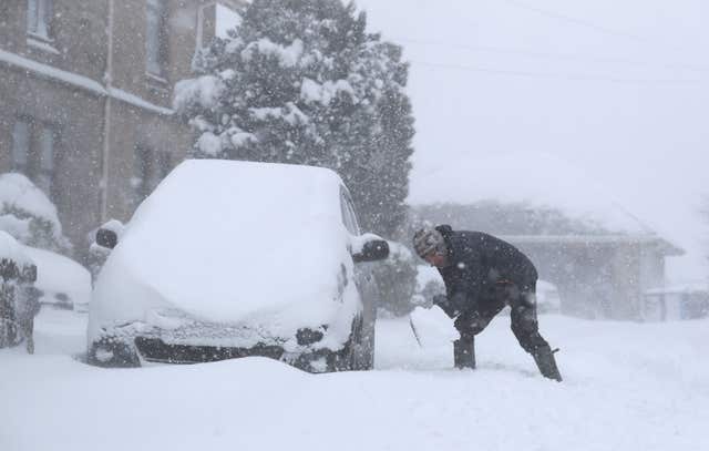 A man tries to dig his car out of snow