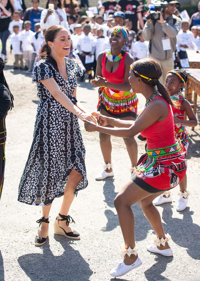 The Duchess of Sussex joins in with dancers as she leaves the Nyanga Township in Cape Town, South Africa, on the first day of their tour of Africa