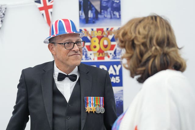 A Holocaust survivors with a hat in the colours of the union flag