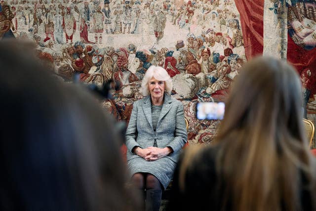 The Queen sitting down with a tapestry backdrop