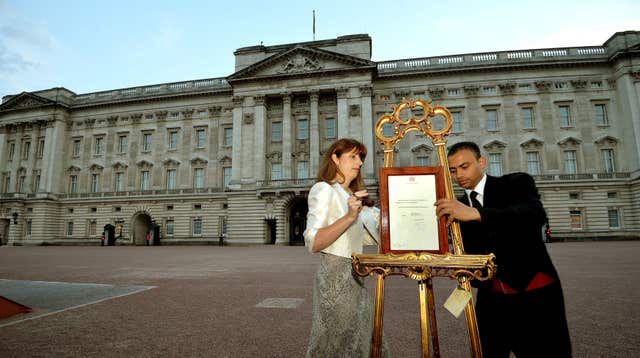 A press secretary and a footman place an easel on the forecourt of Buckingham Palace to announce the birth of Prince George in 2013 (John Stillwell/PA)