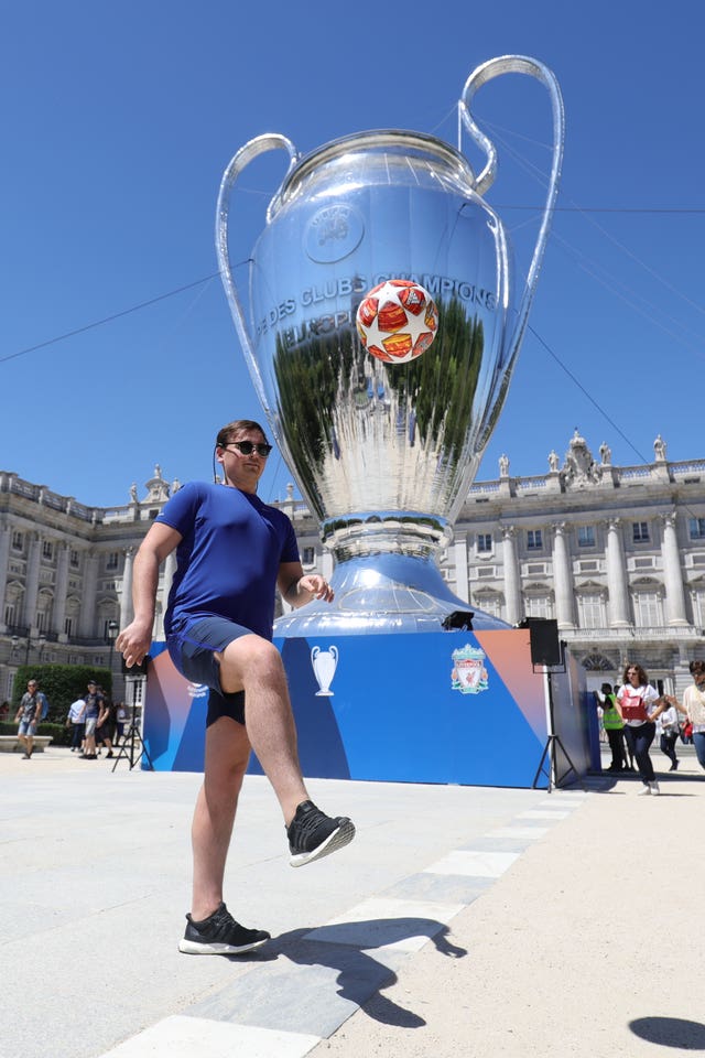 A man kicks a ball in front of an inflatable Champions League cup in Plaza Mayor in Madrid