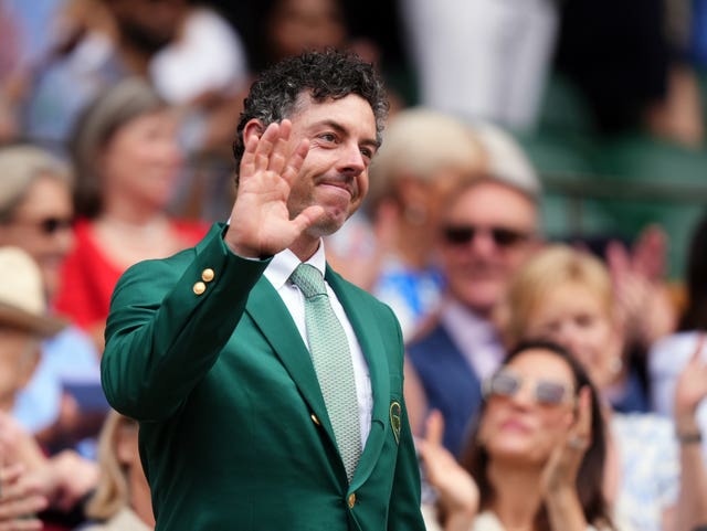 Rory McIlroy, wearing his Masters green jacket, waves