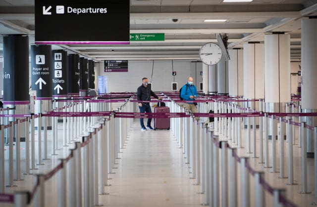 Passengers, wearing a protective face masks, wait at the check-in area at Edinburgh Airport