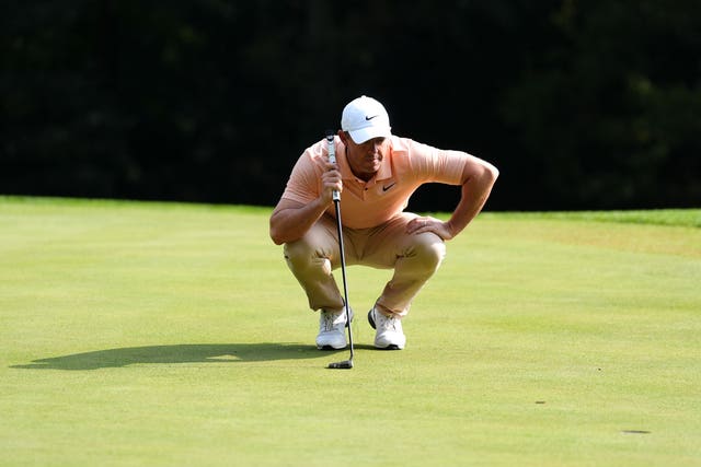 Rory McIlroy crouches down to read a putt on the green