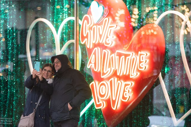 Shoppers take a selfie outside a window display on Oxford Street, in central London