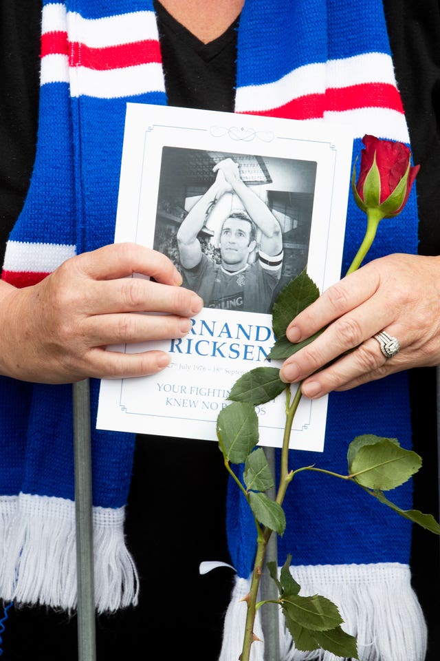 A supporter holds an order of service