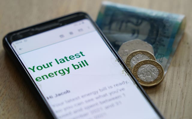 An energy bill displayed on a smartphone, next to coins and notes