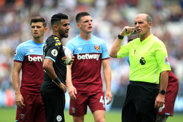 Referee Mike Dean, right, awaits the VAR's verdict as Declan Rice looks on