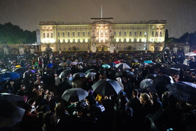 Huge crowds, carrying umbrellas in the rain, gather outside Buckingham Palace as dusk fell on the day the Queen died