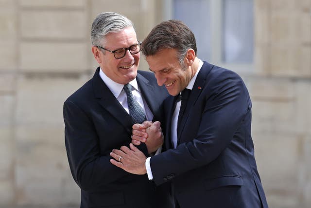 Emmanuel Macron (right) and Sir Keir Starmer smiling as they greet each other