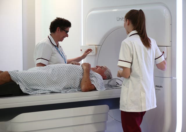 Radiographers Trina Herbert (left), and Gillian Smith help patient Barry Dolling, aged 65, from Selsdon, Surrey, after treatment using a Magnetic Resonance Linear Accelerator (MR Linac) machine