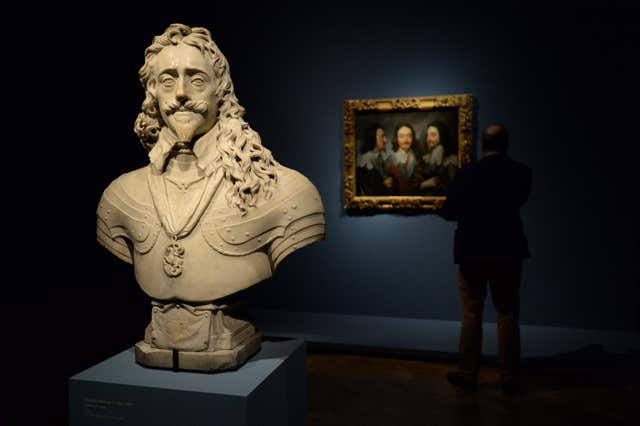 A visitor looks at Charles I In Three Positions’ by Anthony van Dyck, behind a statue of Charles I by Francois Dieussart (Kirsty O’Connor/PA)