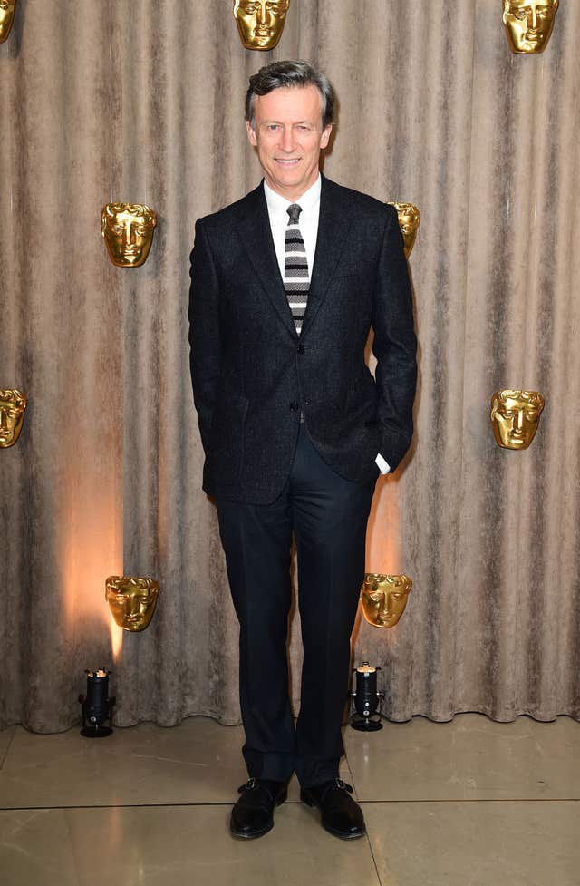 Duncan Kenworthy smiling, in front of the Bafta face logo