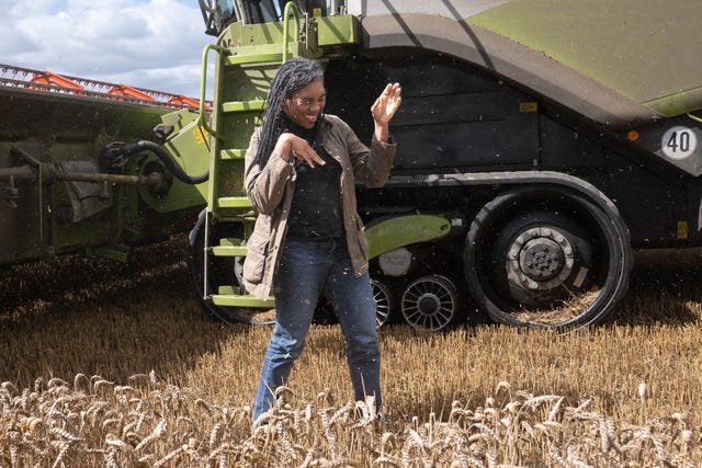 Conservative Party leader Kemi Badenoch closes her eyes and tries to bat away grain dust during a visit to Hall Farm in Little Walden, Essex