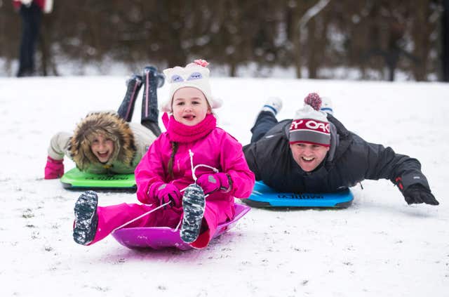 Charlotte Berry (front) sledging with Heidi Fairburn (back left) and Ian Berry (right) in Leeds (Danny Lawson/PA)