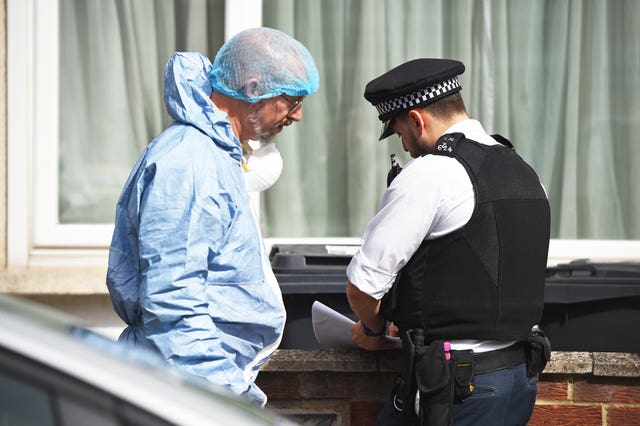 A forensic officer speaks with a police officer at the scene in Raymead Avenue, Thornton Heath, Croydon