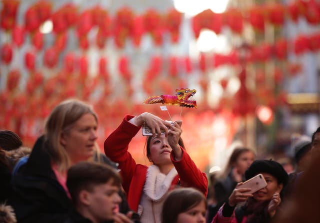 A woman takes a selfie against a backdrop of hanging lanterns in Gerrard Street in Chinatown, London (Yui Mok/PA)