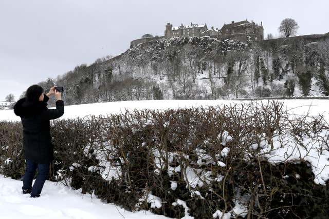 A woman takes a photo of Stirling Castle in the snow (Andrew Milligan/PA)